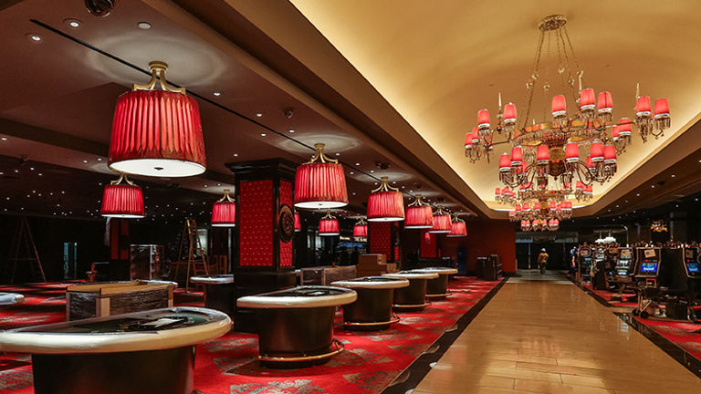 Vibrant shades of red and elegant chandeliers cast a rosy glow over the 40,000-square-foot casino space. // © 2014 Caesars Entertainment