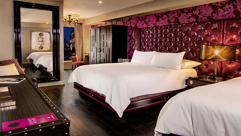 Modeled after a Parisian loft-style apartment, standard rooms have upholstered wall panels, dark parquet flooring and trunk-style furnishings. // © 2014 Caesars Entertainment