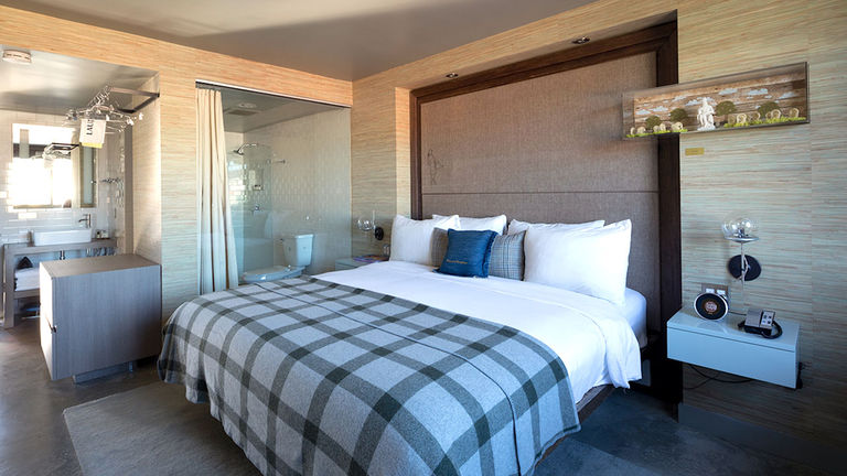 The bathroom in a Robin Room — separated from the bedroom area by a glass wall — treats guests to rainfall showerheads and C.O. Bigelow bath amenities.