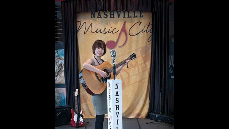 A visitor from Beijing strums a guitar on a stage replica at Nashville’s Visitor Center. // © 2015 Mark Edward Harris