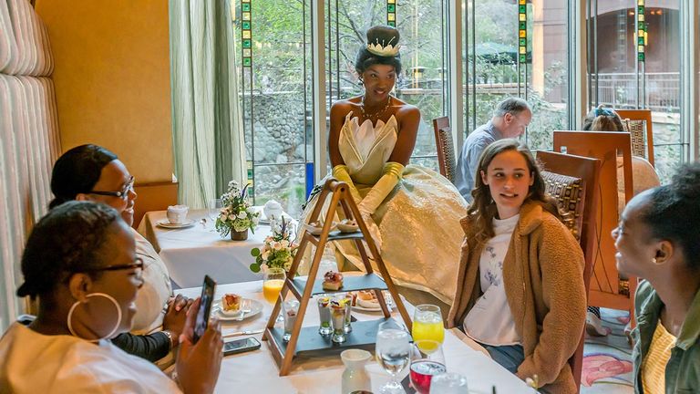 Princess Tiana chats with diners at their table.