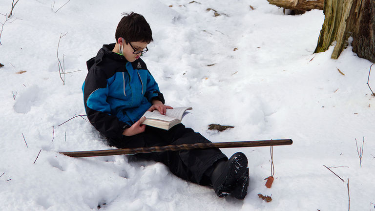 The writer's son was content to read a book in the snow during breaks from the hike.