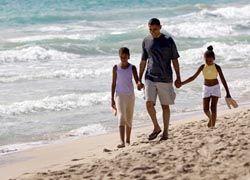President Barack Obama walks on the beach with his daughters Malia, 10, left, and Sasha, 7, during his vacation in Kailua on Oahu.// (C) 2010 AP Photo/Marco Garcia