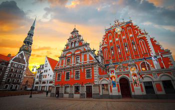 City Hall Square with House of the Blackheads and Saint Peter church in Old Town of Riga in the evening, Latvia (photo via Lindrik / iStock / Getty Images Plus)