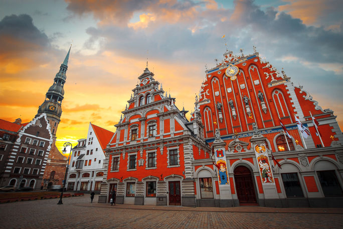 City Hall Square with House of the Blackheads and Saint Peter church in Old Town of Riga in the evening, Latvia (photo via Lindrik / iStock / Getty Images Plus)