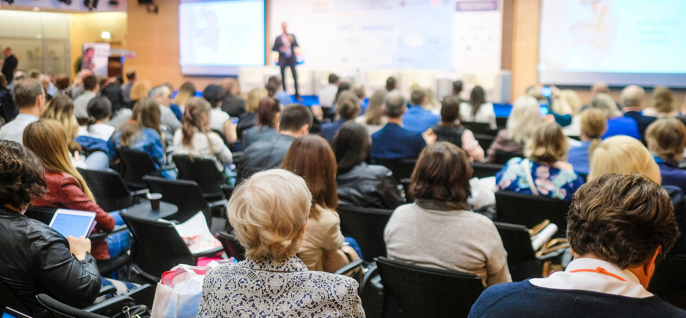 Image: People at a conference. (Photo Credit: Dmitry Vereshchagin / Adobe Stock)