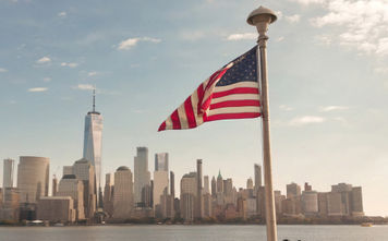 American flag waves in front of New York City skyline