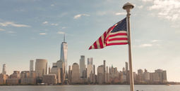 American flag waves in front of New York City skyline