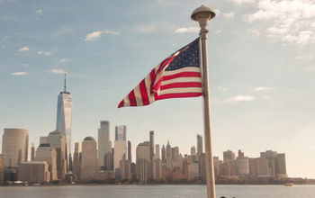 American flag waves in front of New York City skyline