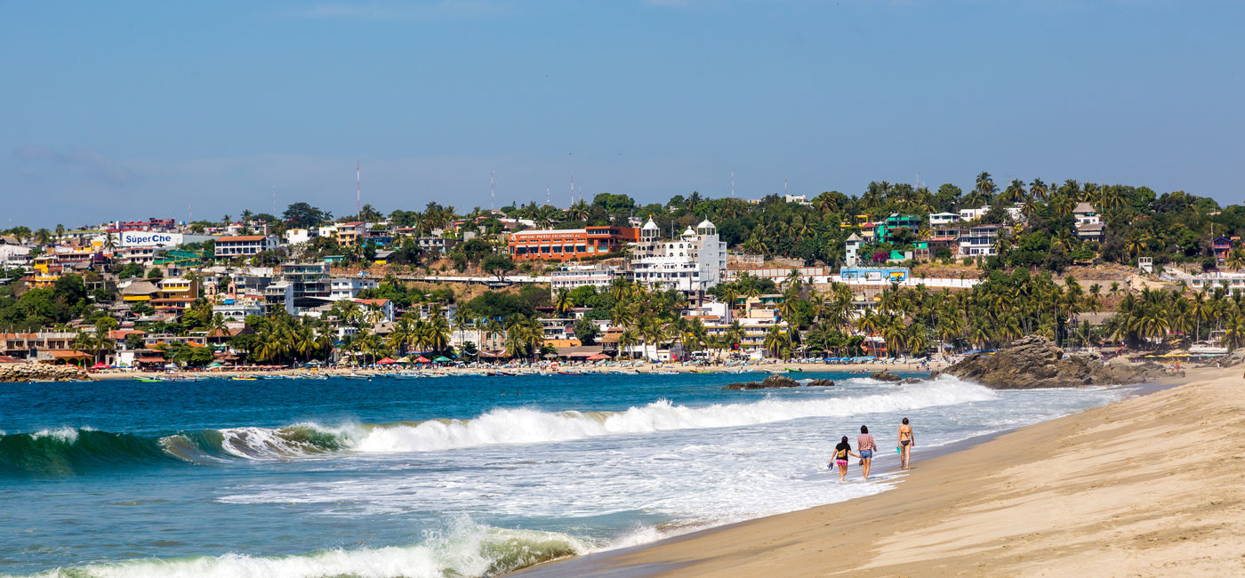 Image: People on the beach in Puerto Escondido, Mexico. (Photo Credit: LMspencer/Adobe)