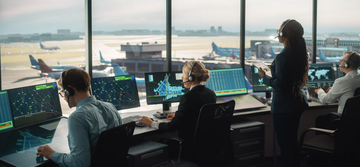 Image: Air traffic controllers working in an airport control tower. (Photo Credit: Adobe Stock/Gorodenkoff)