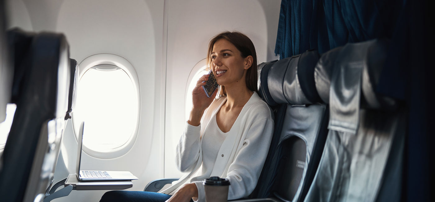 Image: Traveler making an in-flight call. (Photo Credit: Adobe/Viacheslav Yakobchuk)