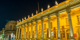 Exterior of neoclassic theatre lit from within at night
