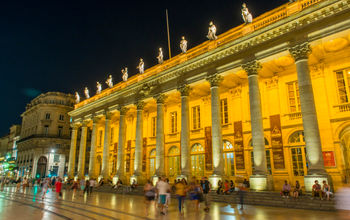 Exterior of neoclassic theatre lit from within at night