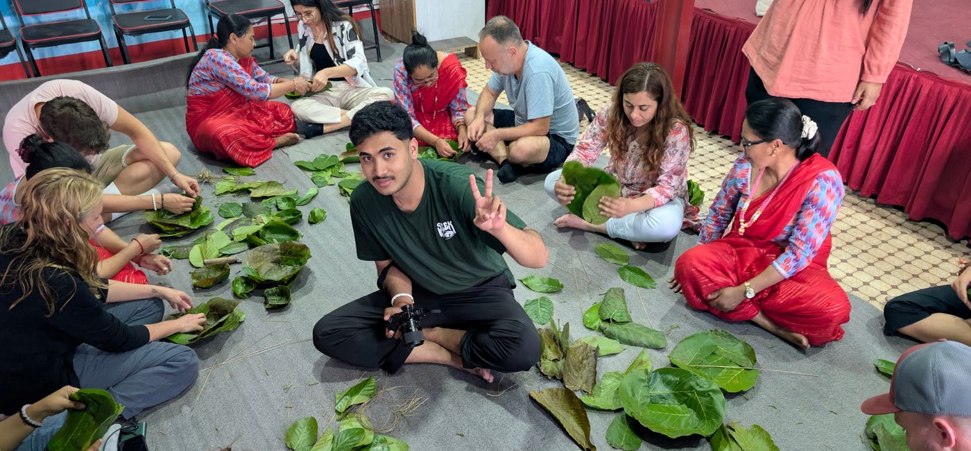 Image: Le photographe Saurav KC entouré d’hôtes du village et de professionnels internationaux du voyage, fabriquant de la vaisselle à partir des feuilles d’un arbre appelé sol, près de Bhaktapur, au Népal (Photo Credit: Bert Archer)