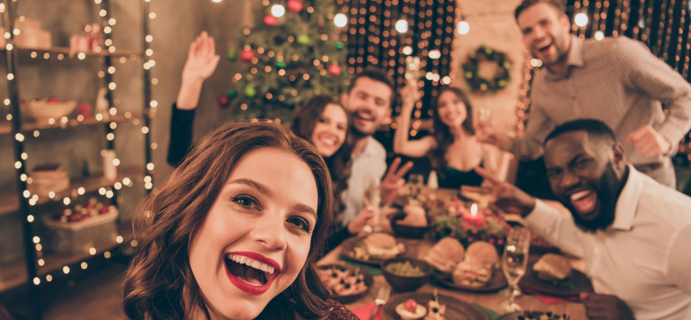 Image: A group of friends celebrating during a holiday gathering (Photo Credit: Adobe Stock/deagreez)