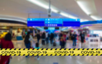 COVID-19 warning across the foreground of an airport terminal.
