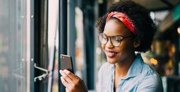 Smiling woman on cellphone over dinner in a bistro