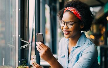 Smiling woman on cellphone over dinner in a bistro