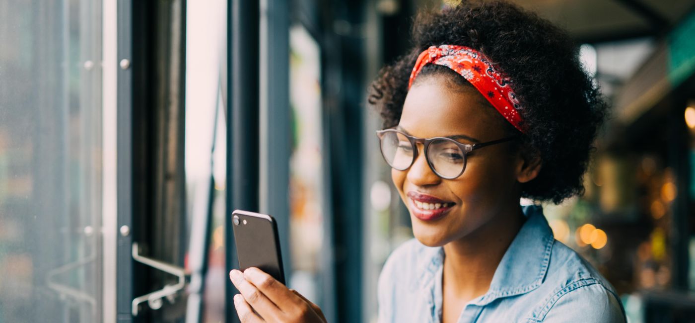 Image: Smiling woman on cellphone over dinner in a bistro (Photo Credit: / iStock / Getty Images Plus)