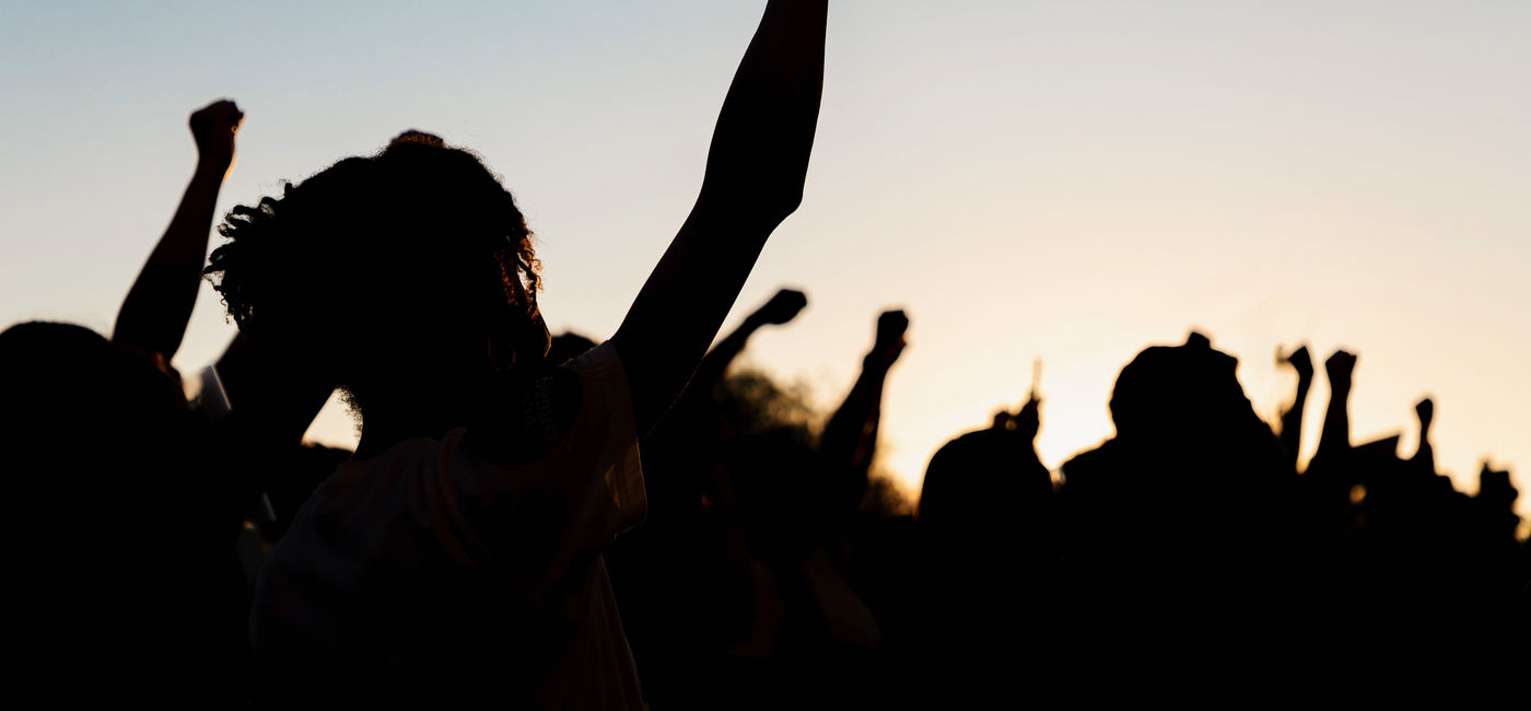 Image: People holding fists up at a protest. (Photo Credit: Ashley / Adobe Stock)