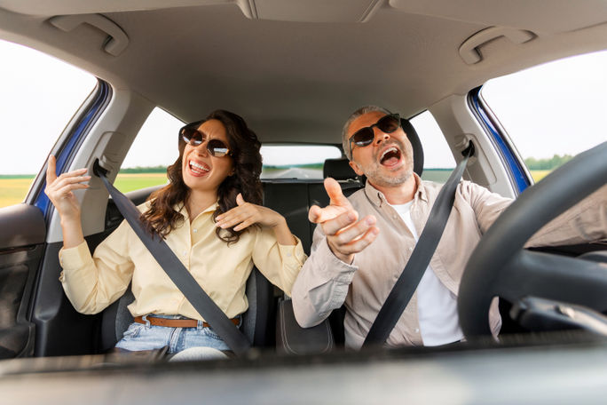 Couple singing along to a road trip playlist Couple singing along to a road trip playlist