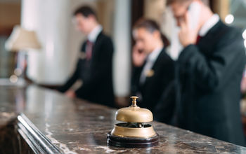Hotel staff working at reception counter with service bell.