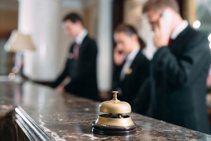 Hotel staff working at reception counter with service bell.  