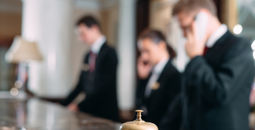 Hotel staff working at reception counter with service bell.