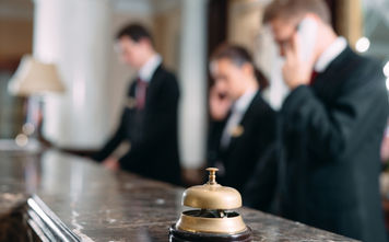 Hotel staff working at reception counter with service bell.