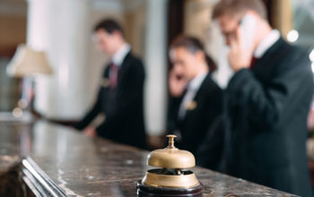 Hotel staff working at reception counter with service bell.
