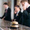 Hotel staff working at reception counter with service bell.  