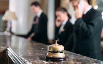 Hotel staff working at reception counter with service bell.