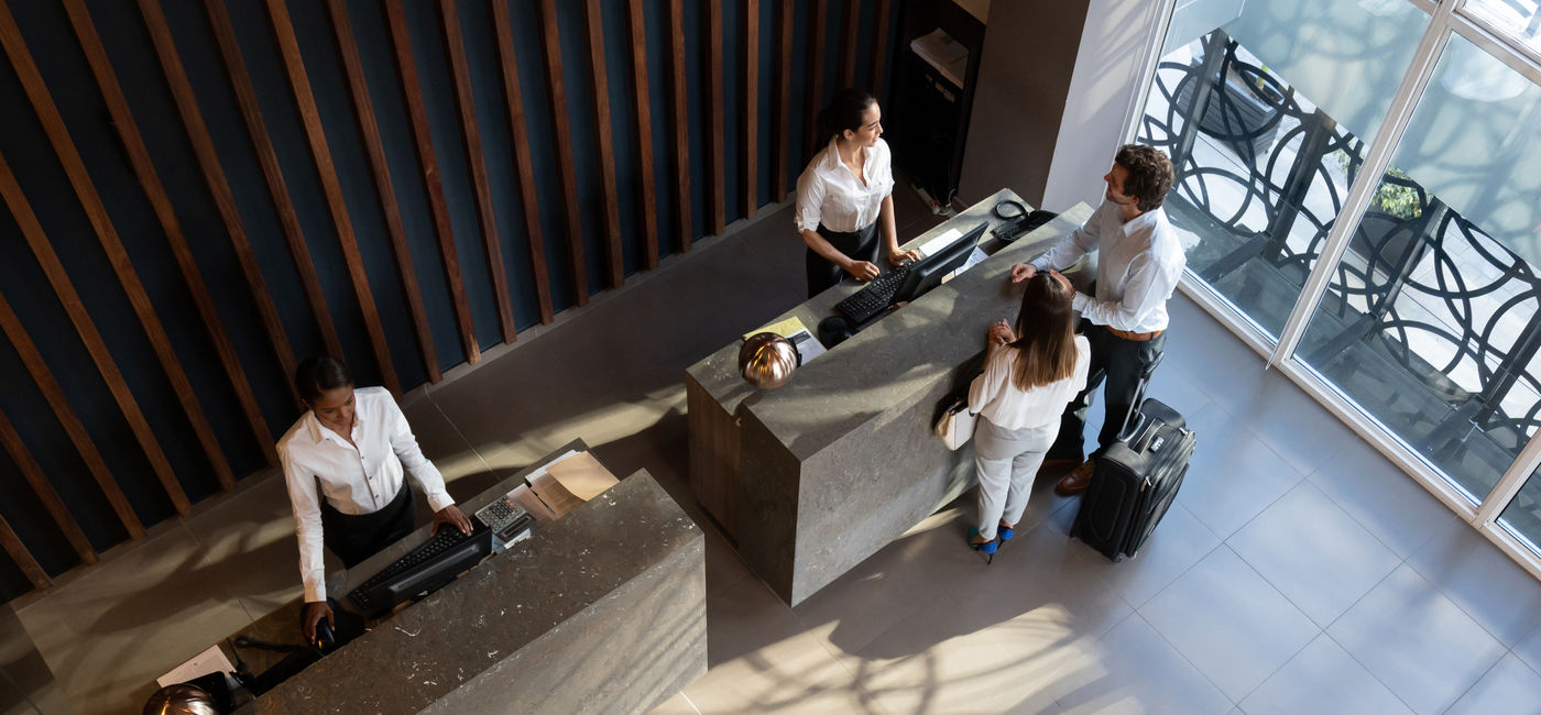 Image: People checking in at hotel. (photo via Hispanolistic / E+)
