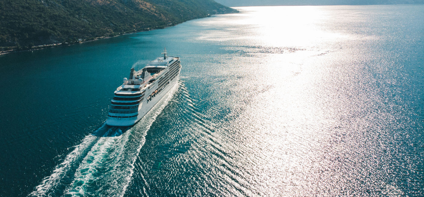 Image: Cruise ship sailing off in the distance (Photo Credit: Adobe)