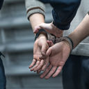 Someone under arrest in handcuffs.