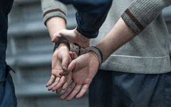 Someone under arrest in handcuffs.