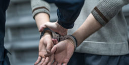 Someone under arrest in handcuffs.