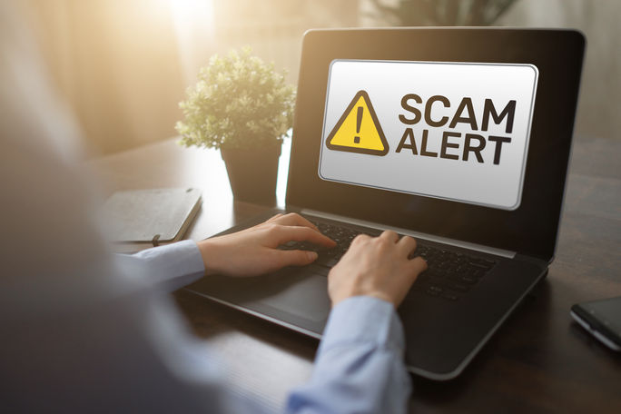 Beware of travel scams. Scam alert displayed on a laptop computer.