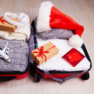 Suitcase with Christmas gifts and a Santa hat.