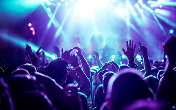 Crowd raising their hands at concert (Photo via bernardbodo / iStock / Getty Images Plus)