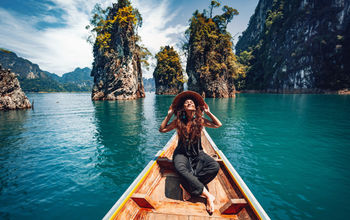 happy young woman tourist in asian hat on the boat at lake