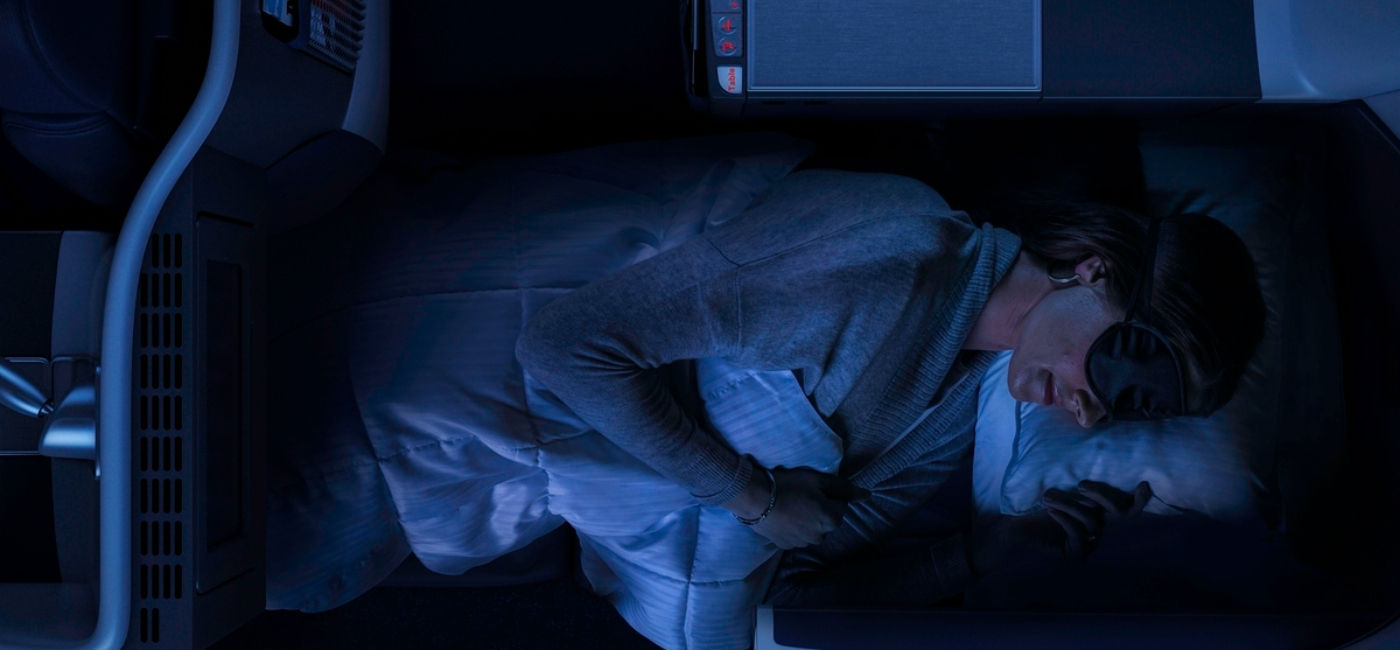 Image: A woman rests in a Delta One flat bed seat.  (Photo Credit: Delta Air Lines)