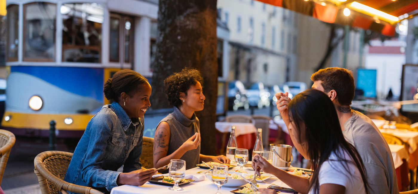 Image: Group dining in Lisbon, Portugal. (Photo Credit: Adobe/PintoArt)
