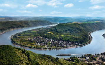 A Uniworld Boutique River Cruises ship sails around a bend in the Rhine River near Boppard, Germany.