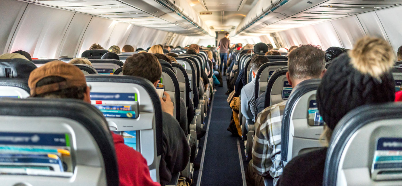 Image: Passengers seated inside of a commercial passenger airplane. (Photo Credit: Daniel Avram / Adobe Stock)
