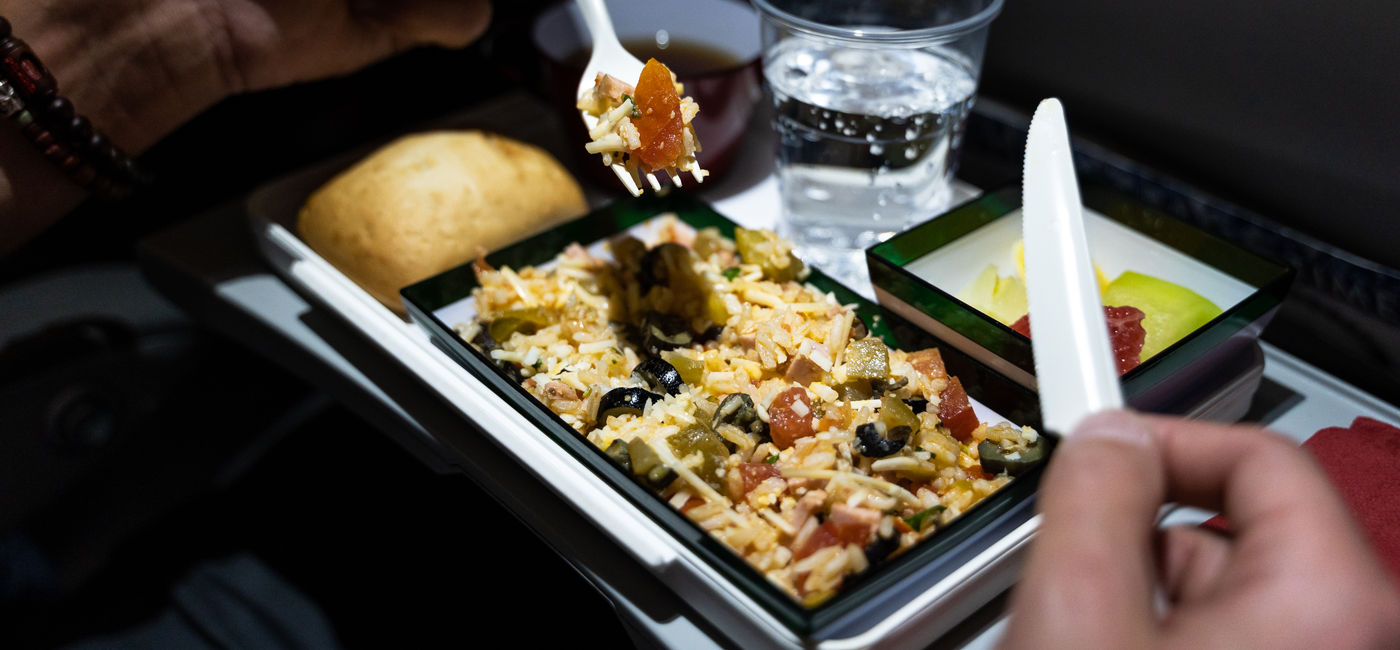 Image: Airline passenger eats an in-flight meal. (Photo Credit: NDStock/Adobe)