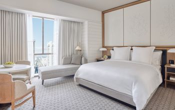 Hotel guest room with white bed, luxury furnishings, and city view