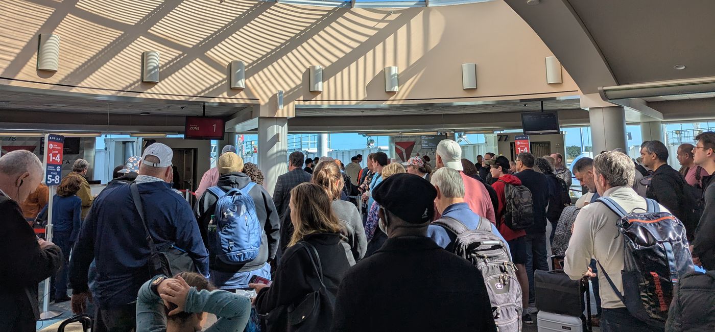 Image: Travelers crowd together before boarding airplane (Photo Credit: Eric Bowman)