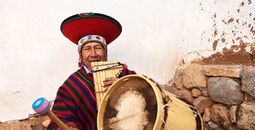Peruvian man playing a pan flute and drums.